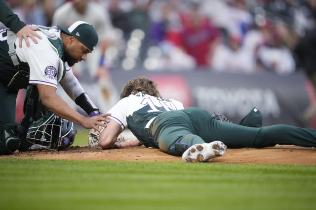 Colorado Rockies catcher Elias Diaz, left, checks on starting pitcher Ryan Feltner, who lies on the mound after getting hit by a single off the bat of Philadelphia Phillies' Nick Castellanos during the second inning of a baseball game Saturday, May 13, 2023, in Denver. (AP Photo/David Zalubowski)
