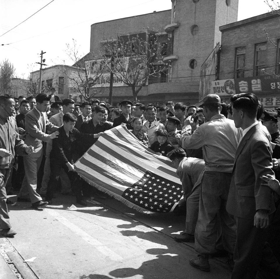 FILE - Students demonstrating in Seoul, South Korea carefully fold a U.S. flag before handing it to Associated Press staff photographer Hal Buell during rioting in the South Korean capital on April 25, 1960. Buell, who led The Associated Press' photo operations from the darkroom era into the age of digital photography over a four-decade career with the news organization that included 12 Pulitzer Prizes and running some of the defining images of the Vietnam War, has died. Buell died Monday, Jan. 29, 2024, in Sunnyvale, Calif., where his daughter lived, after battling pneumonia. He was 92.(AP Photo/Hal Buell, File)