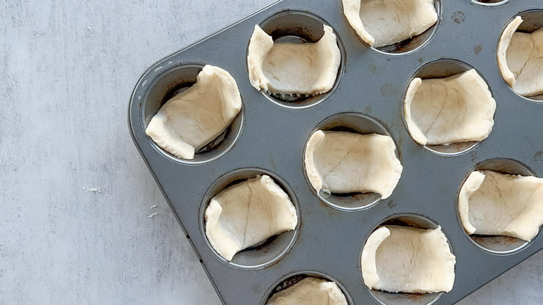 dough in muffin tin slots