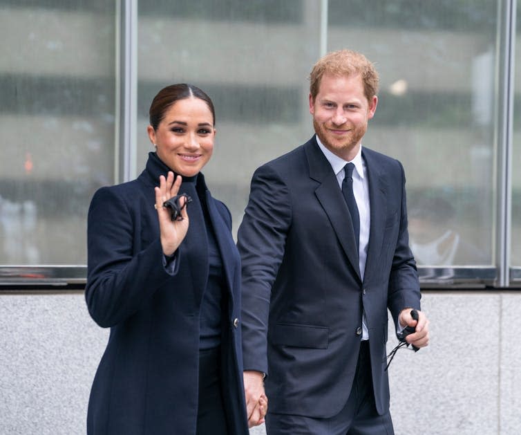 Meghan Markle waving alongside Prince Harry