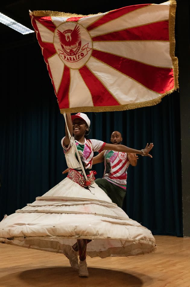 Amber Ogunsanya-William (20) is this year's Porta-Bandeira, meaning Flag Bearer, for the Paraiso School of Samba — a role that is considered royalty in Brazilian culture. She is accompanied by Chirag Goyate, the Mestre Sala, and together they will open and lead Paraiso in this year's Notting Hill Carnival Parade. 