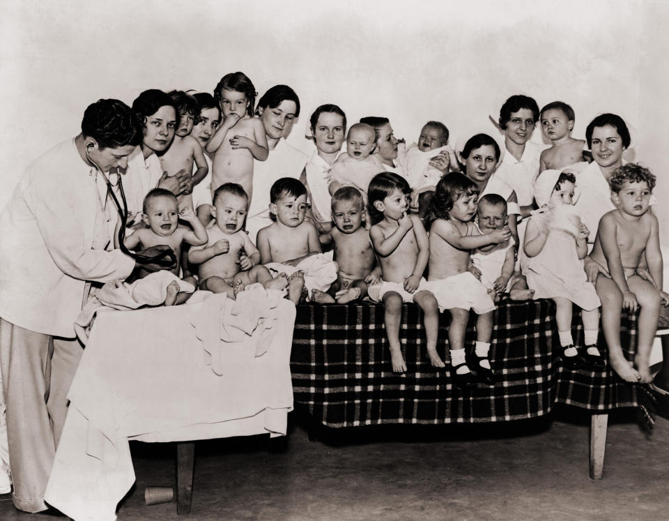 Fourteen infants await examination by a doctor in a 