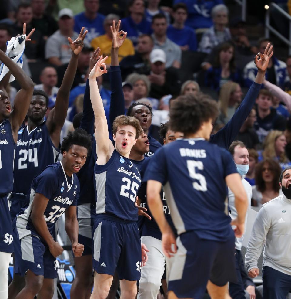 The Saint Peter&#39;s bench erupts as Daryl Banks III (5) hits a three-pointer against Kentucky during their first-round NCAA Tournament game at the Gainbridge Fieldhouse in Indianapolis, Indiana on March 17, 2022. Saint Peter&#39;s won 85-79 in OT.