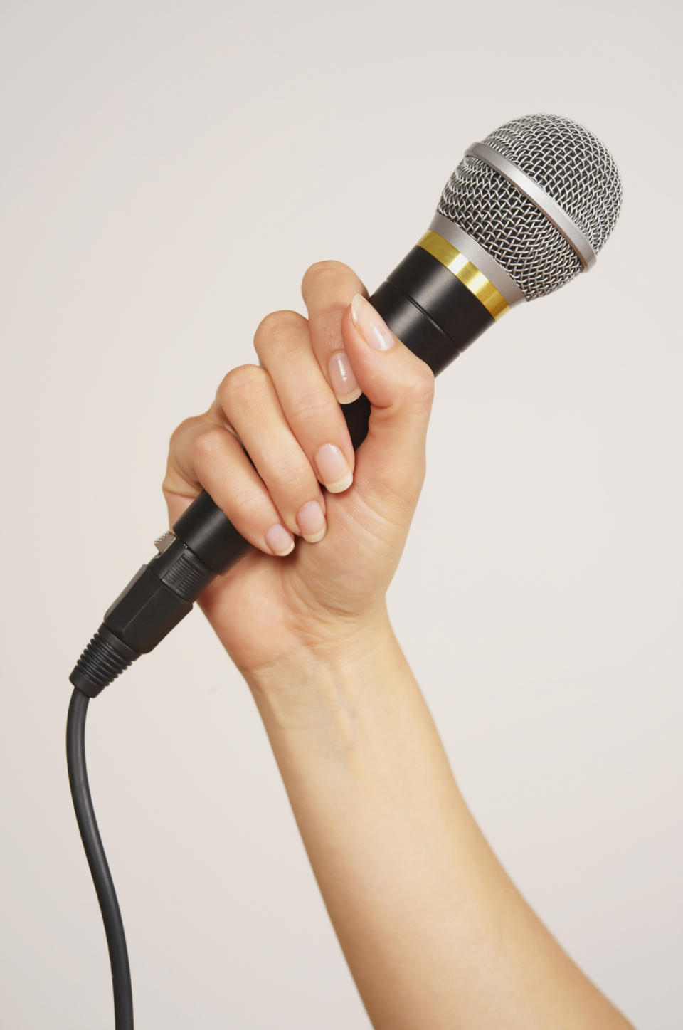 A hand holds a microphone, possibly preparing for a speech or interview