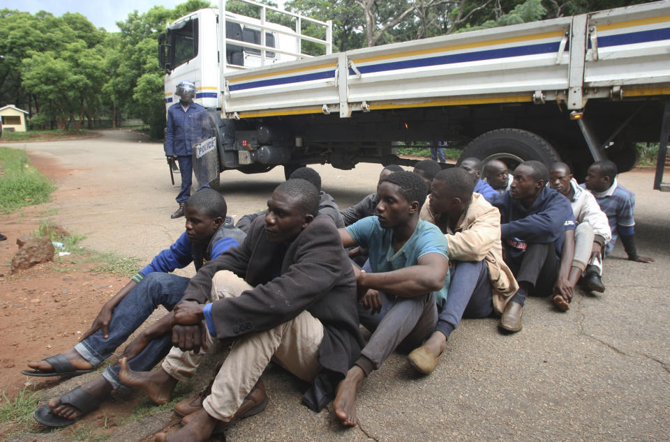 A policeman stands guard as some of the people arrested during demonstrations over the hike in fuel prices, make their court appearance at the magistrates courts in Harare, Zimbabwe, Wednesday, Jan,16, 2019. Some dozens of people appeared in court and were charged with public violence and a human rights group in Zimbabwe says a few people were killed in clashes between demonstrators protesting fuel hikes and security forces who opened fire on some crowds. (AP Photo/Tsvangirayi Mukwazhi)