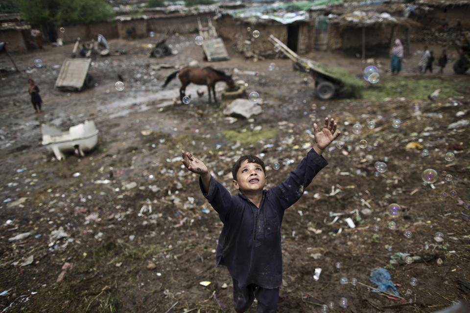 <p>An Afghan refugee child chases bubbles released by other children, while playing on the outskirts of Islamabad, Pakistan, Aug. 8, 2014. (Photo: Muhammed Muheisen/AP) </p>