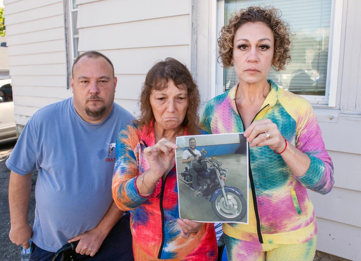 Rosemary Gleason, center, holds a photograph of her son, David, at the spot where he was killed last year in a motorcycle crash on Sunderland Road. She is joined by her brother, John Gleason, and Lisa Luccarelli, the mother of David Gleason's girlfriend.