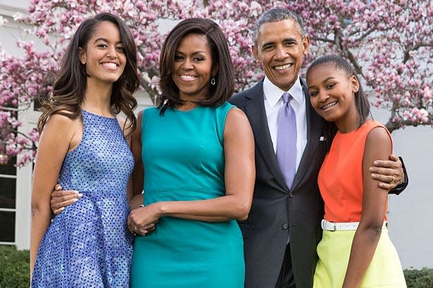 Former President Barack Obama and former first lady Michelle Obama stand with their daughters, Malia and Sasha.