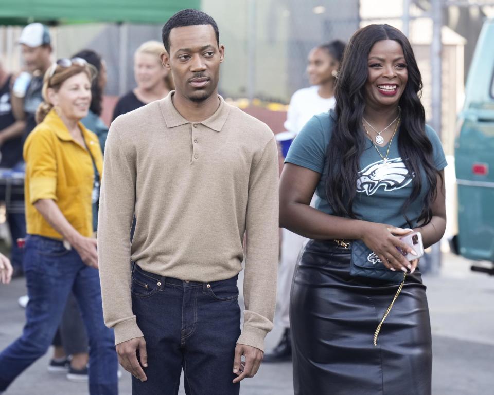 a man looking unamused and a woman smiling in a parking lot