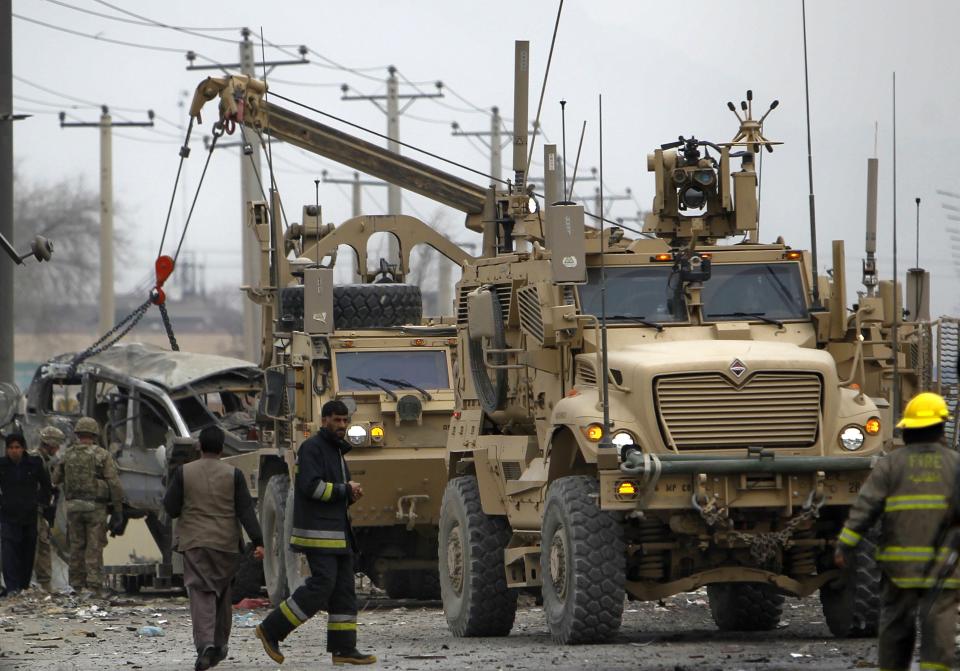 An armoured vehicle hit by a bomb attack is lifted by a U.S. truck in Kabul