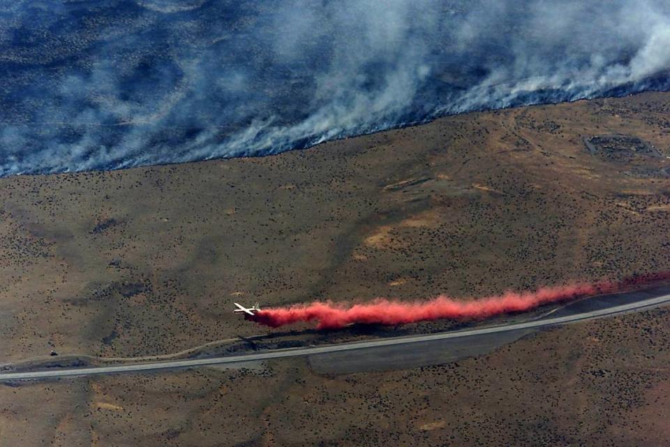 A tanker plane drops a load of fire retardant in June, 2000 along the Hanford Highway. An estimated 192,000 acres burned in the fire, which was caused by a fiery fatal head-on collision