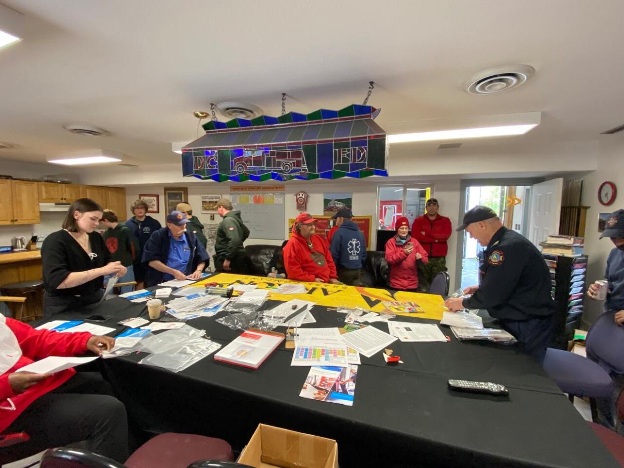 Over 30 local emergency responders gathered at the fire hall in Dawson City, Yukon, on Wednesday to put together 1,000 emergency information kits. The kits will be handed out to residents this weekend. (Chris MacIntyre/CBC - image credit)