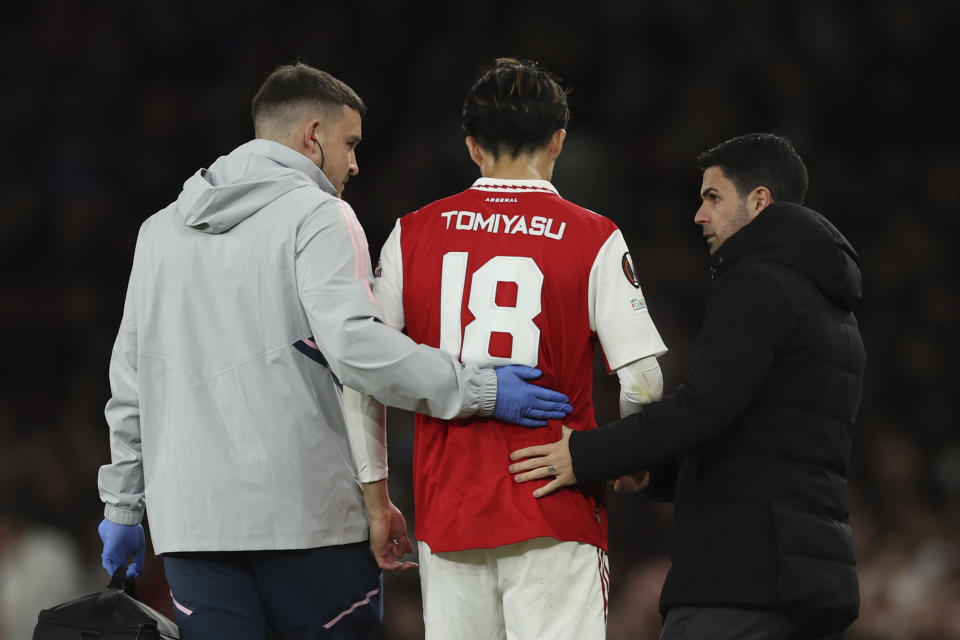 Arsenal's Takehiro Tomiyasu, center, leaves the field with medic, left, and Arsenal's manager Mikel Arteta during the Europa League round of 16, second leg, soccer match between Arsenal and Sporting CP at the Emirates stadium in London, Thursday, March 16, 2023. (AP Photo/Ian Walton)