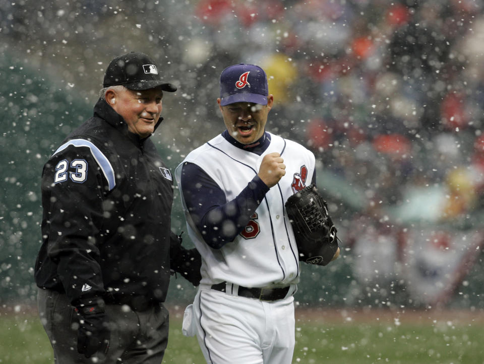 FIULE - In this April 6, 2007, file photo, umpire Rick Reed (23) laughs with Cleveland Indians pitcher Paul Byrd (36) after snow delayed the baseball game between the Indians and the Seattle Mariners, in Cleveland. To baseball fans, opening day is an annual rite of spring that evokes great anticipation and warm memories. This year's season was scheduled to begin Thursday, March 26, 2020, but there will be no games for a while because of the coronavirus outbreak. (AP Photo/Tony Dejak, File)