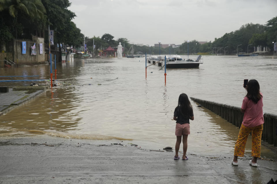 Girls look at a flooded riverside park due to enhanced rains brought about by Typhoon Doksuri on Thursday, July 27, 2023, in Marikina city, Philippines. Typhoon Doksuri lashed northern Philippine provinces with ferocious wind and rain Wednesday, leaving several people dead and displacing thousands of others as it blew roofs off houses, flooded low-lying villages and triggered dozens of landslides, officials said. (AP Photo/Aaron Favila)