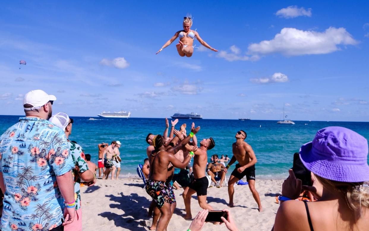 A college athlete is thrown in the air by a group of men on the beach to celebrate spring break - MARIA ALEJANDRA CARDONA /REUTERS