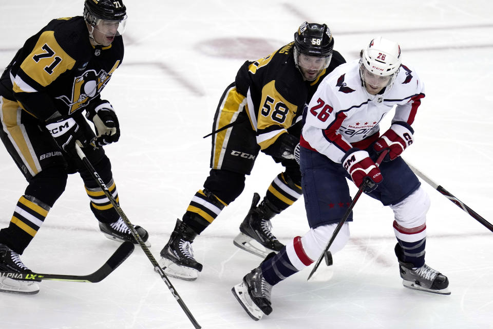 Washington Capitals' Nic Dowd (26) swats at the airborne puck with Pittsburgh Penguins' Kris Letang (58) defending during the first period of an NHL hockey game in Pittsburgh, Saturday, March 25, 2023. (AP Photo/Gene J. Puskar)