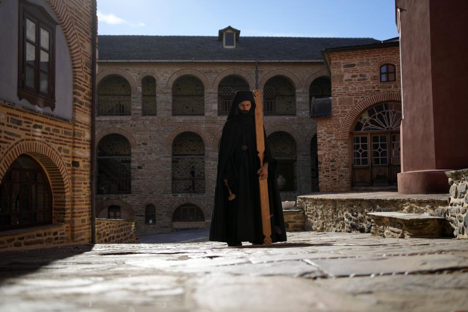 A monk using a mallet and plank to summon monks and visitors to the afternoon prayers, pauses at the Pantokrator Monastery in the Mount Athos, northern Greece, on Thursday, Oct. 13, 2022. Deep inside a medieval fortified monastery in the Mount Athos monastic community, researchers are for the first time tapping a virtually unknown treasure: thousands of Ottoman-era manuscripts that include the oldest of their kind in the world. (AP Photo/Thanassis Stavrakis)