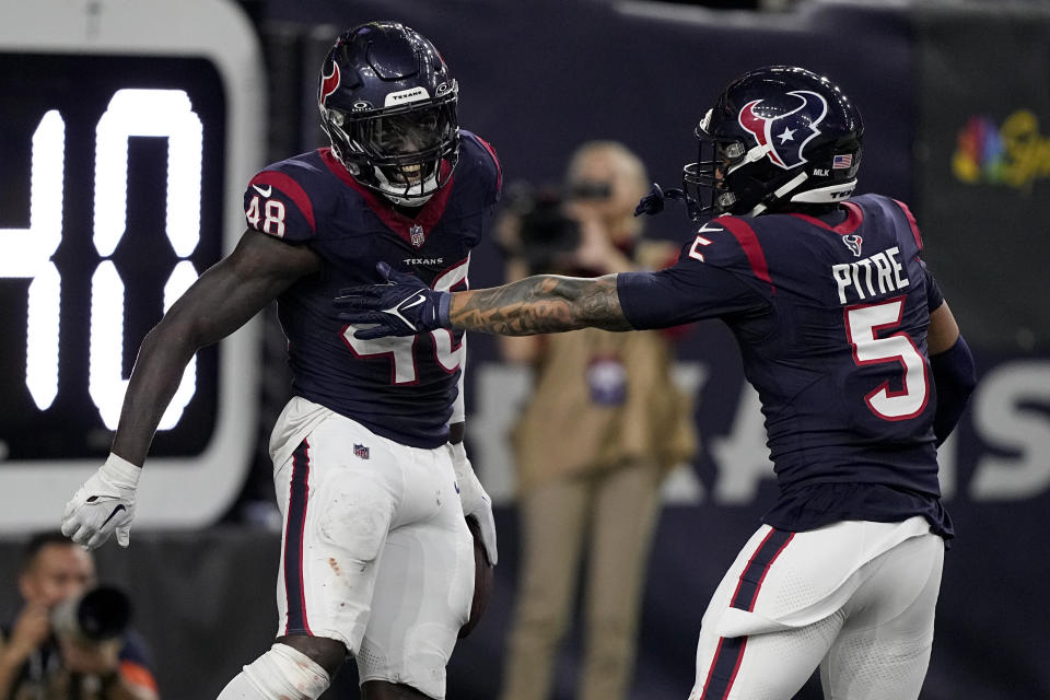 Houston Texans linebacker Christian Harris celebrates with safety Jalen Pitre (5) after scoring on an interception against the Cleveland Browns during the second half of an NFL wild-card playoff football game Saturday, Jan. 13, 2024, in Houston. (AP Photo/David J. Phillip)