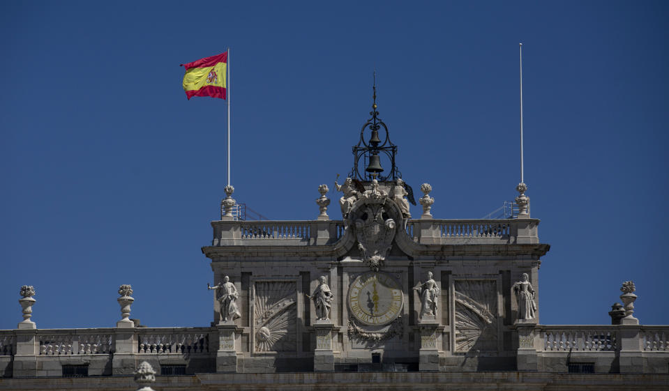 A Spanish flags flies at the Royal Palace in Madrid, Spain, Tuesday, Aug. 4, 2020. Speculation over the whereabouts of former monarch Juan Carlos is gripping Spain, a day after he announced he was leaving the country for an unspecified destination amid a growing financial scandal. (AP Photo/Manu Fernandez)