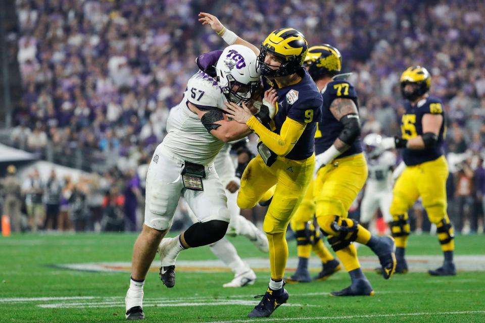 TCU linebacker Johnny Hodges (57) hits Michigan quarterback J.J. McCarthy (9) after a pass during the first half at the Fiesta Bowl at State Farm Stadium in Glendale, Ariz. on Saturday, Dec. 31, 2022.