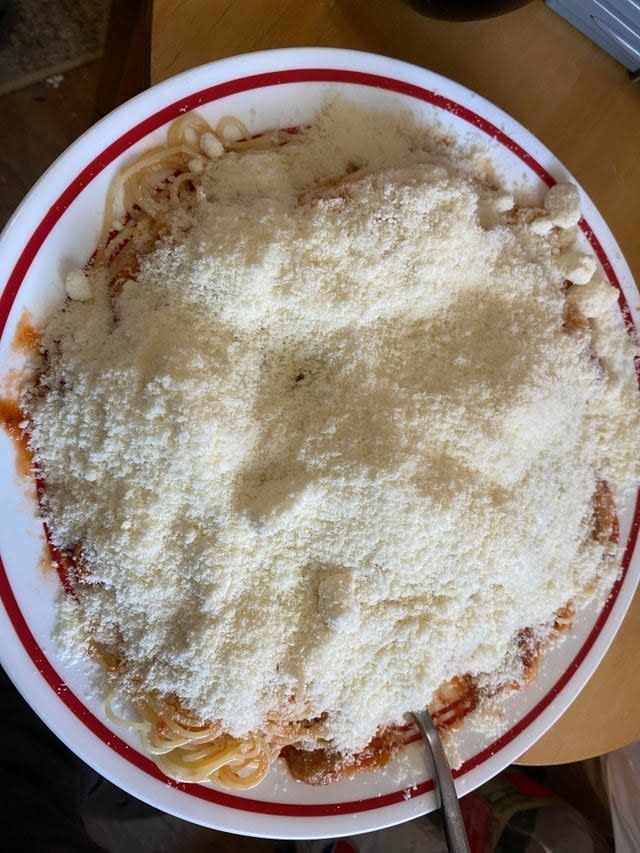 A plate of spaghetti with a ton of Parmesan cheese.