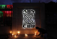 An employee lights candles in front of the headquarters of broadcast network ABS-CBN on Tuesday, May 5, 2020, in Manila, Philippines. A government agency has ordered the country's leading broadcast network, which the president has targeted for its critical news coverage, to halt operations. (AP Photo/Aaron Favila)