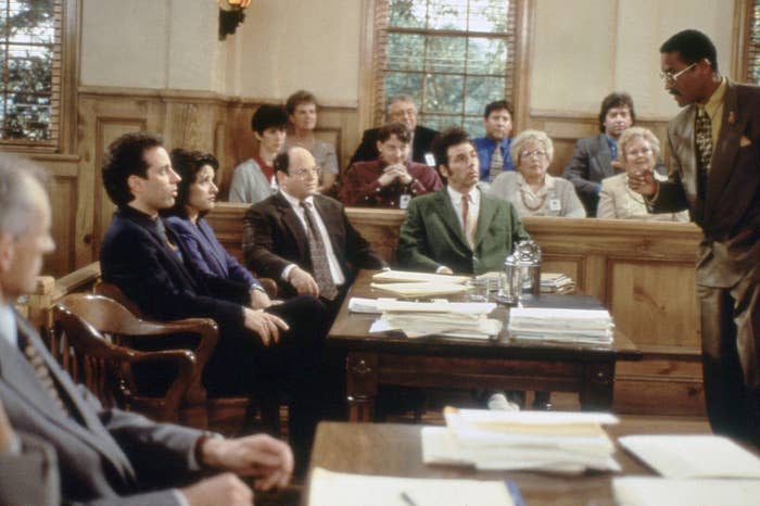The cast sits in a courthouse