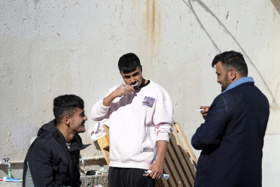 Migrants from Afghanistan gather at an old school used as a temporary shelter on the island of Kythira, southern Greece, Friday, Oct. 7, 2022. Strong winds were hampering rescue efforts at two Greek islands Friday for at least 10 migrants believed to be missing after shipwrecks left more than 20 people dead, officials said. (AP Photo/Thanassis Stavrakis)