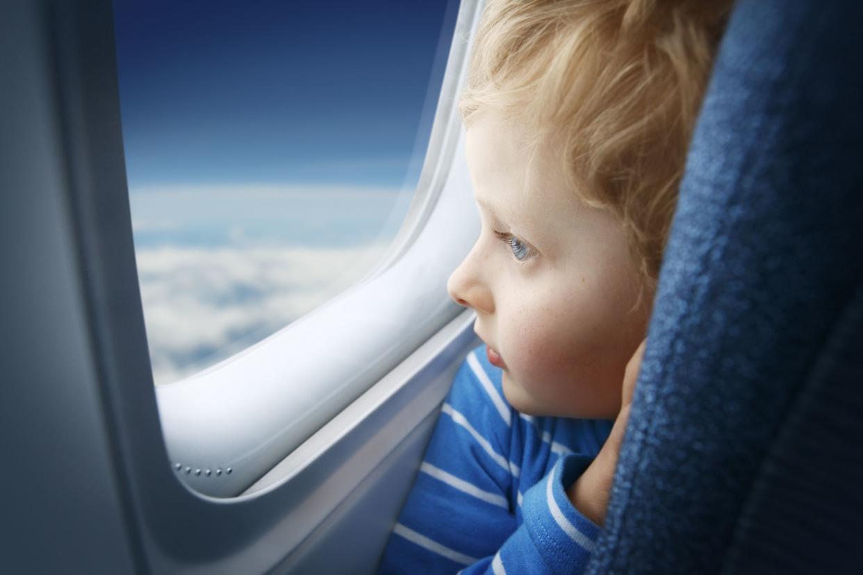 child looking out window on airplane