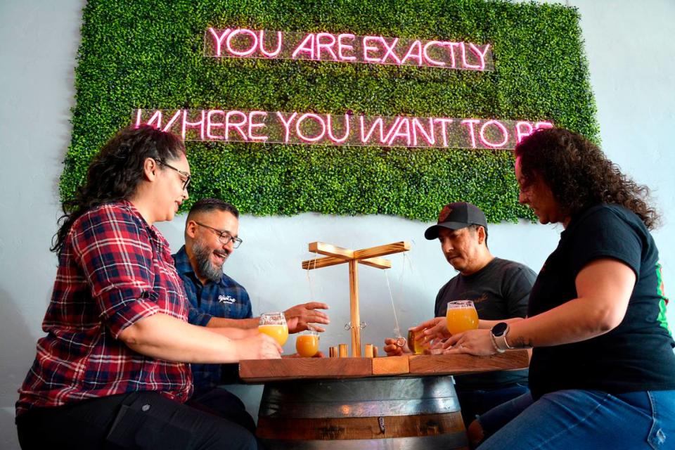 WhichCraft, a new craft brew taproom, has opened in downtown Gustine, California. Co-owners and married couples (L-R) Jackie and Sam De La Cruz and Joe and Lizett Garcia play a table game inside the space.