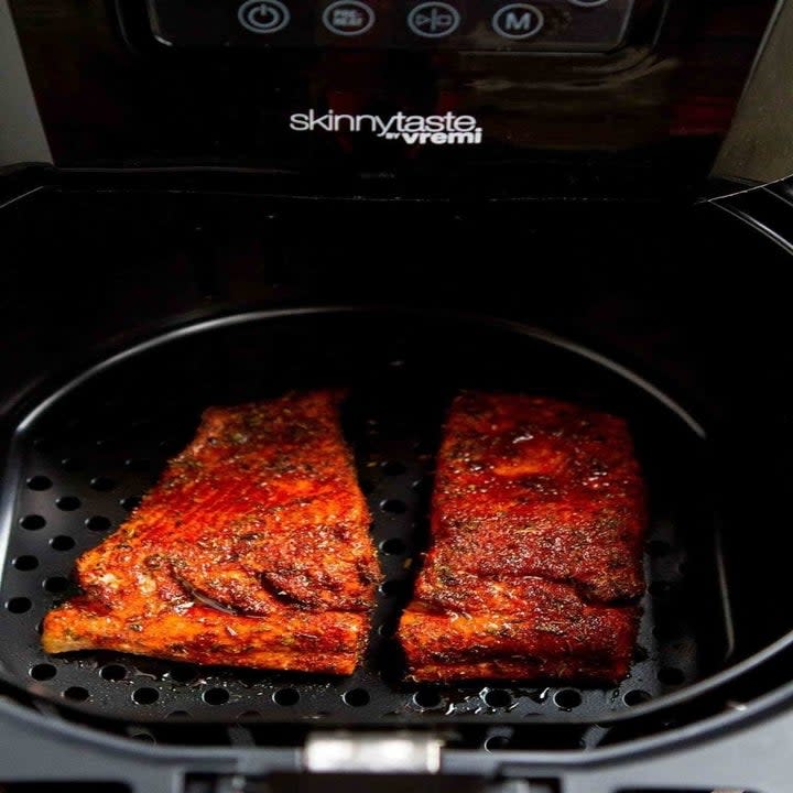 Two pieces of blackened salmon in an air fryer.