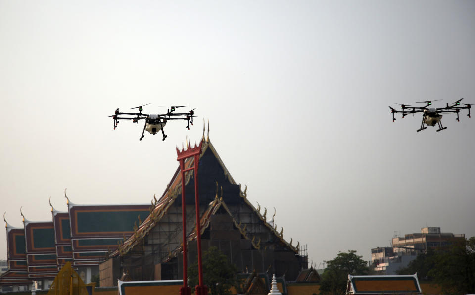 Water-spraying drones fly over the Suthat Temple in Bangkok, Thailand, Thursday, Jan. 31, 2019. A fleet of drones, trucks and small planes are spraying water to try to reduce dust around Bangkok while the governor invited critics to brainstorm better ideas to improve the air quality in the Thai capital. (AP Photo/Sakchai Lalit)