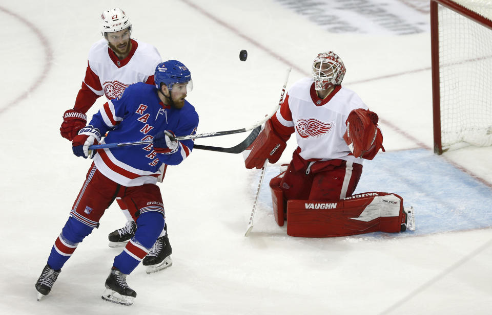 From left to right, Detroit Red Wings center Michael Rasmussen, New York Rangers left wing Alexis Lafreniere and Red Wings goalie Alex Nedeljkovic watch the flying puck during the third period of an NHL hockey game Sunday, Nov. 6, 2022, in New York. (AP Photo/John Munson)