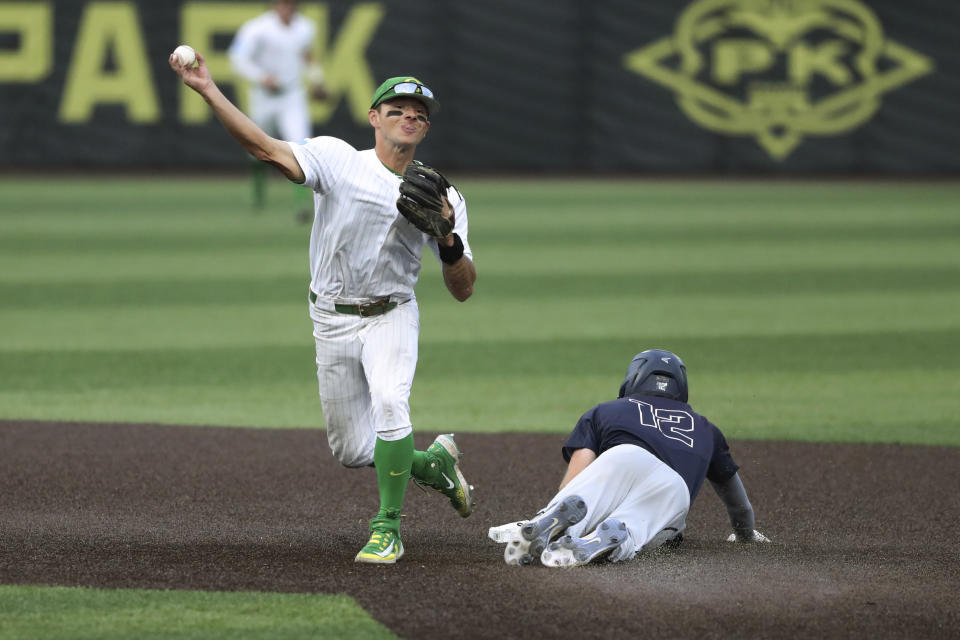 Oregon infielder Gavin Grant (5) throws to first base to complete a double play after forcing out Oral Roberts' Mac McCroskey (12) at second base during the ninth inning of an NCAA college baseball tournament super regional game Friday, June 9, 2023, in Eugene, Ore. (AP Photo/Amanda Loman)