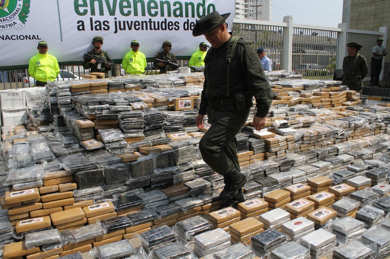 A police officer walks through a display of seized packages of cocaine 