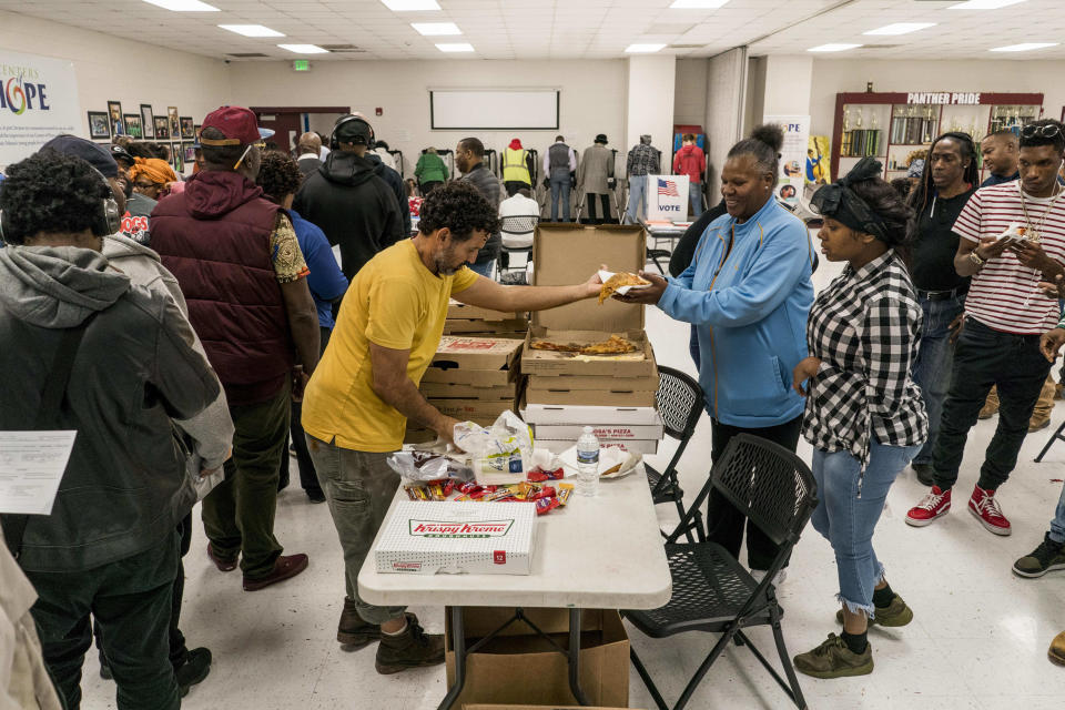 Nonprofit Pizza to the Polls helped deliver more than 10,000 pizzas to voters braving long lines nationwide yesterday. Here, a volunteer hands out pizza to voters in Atlanta, Ga. (Photo: Melina Mara/Washington Post via Getty Images)