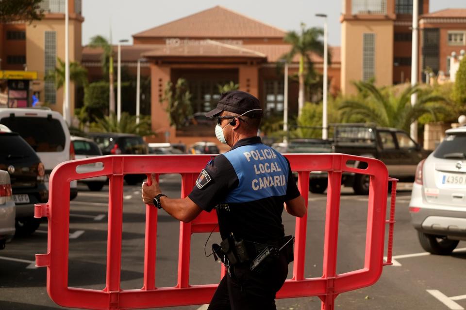 A Spanish police officer sets a barrier blocking the access to the H10 Costa Adeje Palace hotel in Tenerife (AP)