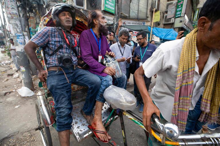 Fotógrafos heridos son transportados en un rickshaw en Daca (Photo by AFP)