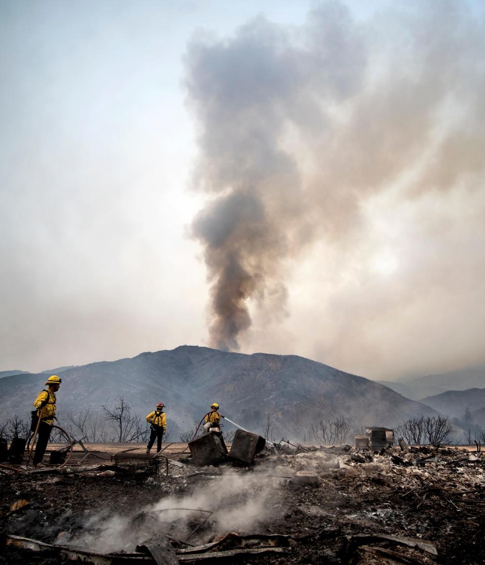 Fountain Valley, Caif., firefighters extinguish hot spots at a structure destroyed by the El Dorado wildfire on Monday, Sept. 7, 2020, near Yucaipa, Calif. A couple's plan to reveal their baby's gender went up not in blue or pink smoke but in flames when the device they used sparked a wildfire east of Los Angeles. The fire started Saturday morning in dry grasses at El Dorado Ranch Park, a rugged natural area in the city of Yucaipa.