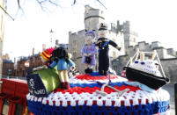 A knitted top cover for a post box depicting Britain's Queen Elizabeth II and her husband Prince Philip in Windsor, England, Friday, April 16, 2021. Prince Philip husband of Britain's Queen Elizabeth II died April 9, aged 99, his funeral will take place Saturday at Windsor Castle in St George's Chapel. The knitted top show some of Prince Philips favorites: the Royal Yacht Britannia, right, the Duke of Edinburgh award scheme for young people and his hobby of carriage driving . (AP Photo/Alastair Grant)