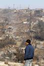 A resident surveys the damage after a forest fire burned homes in Valparaiso city, northwest of Santiago, April 13, 2014. At least 11 people were killed and 500 houses destroyed over the weekend by a fire that ripped through parts of Chilean port city Valparaiso, as authorities evacuated thousands and used aircraft to battle the blaze. REUTERS/Eliseo Fernandez (CHILE - Tags: ENVIRONMENT DISASTER)