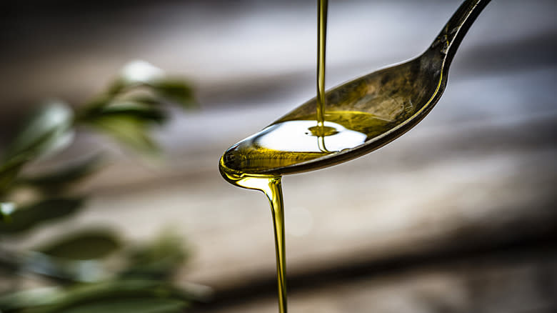 olive oil pouring off spoon