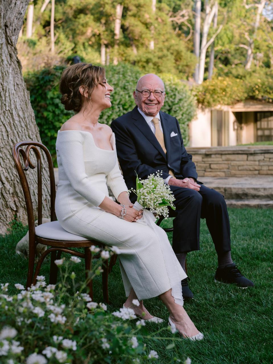 Elena Zhukova and Ruper Murdoch sitting on chairs and laughing together at their wedding.