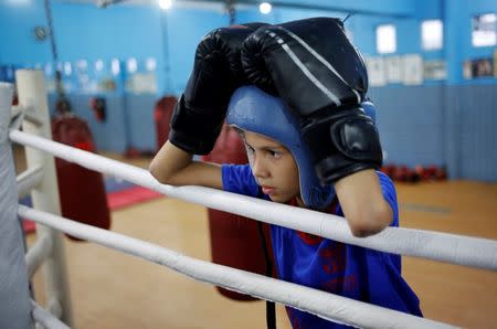 A child looks at other children practicing on a boxing ring during an exercise session at a boxing school, in the Mare favela of Rio de Janeiro, Brazil, June 2, 2016. REUTERS/Nacho Doce