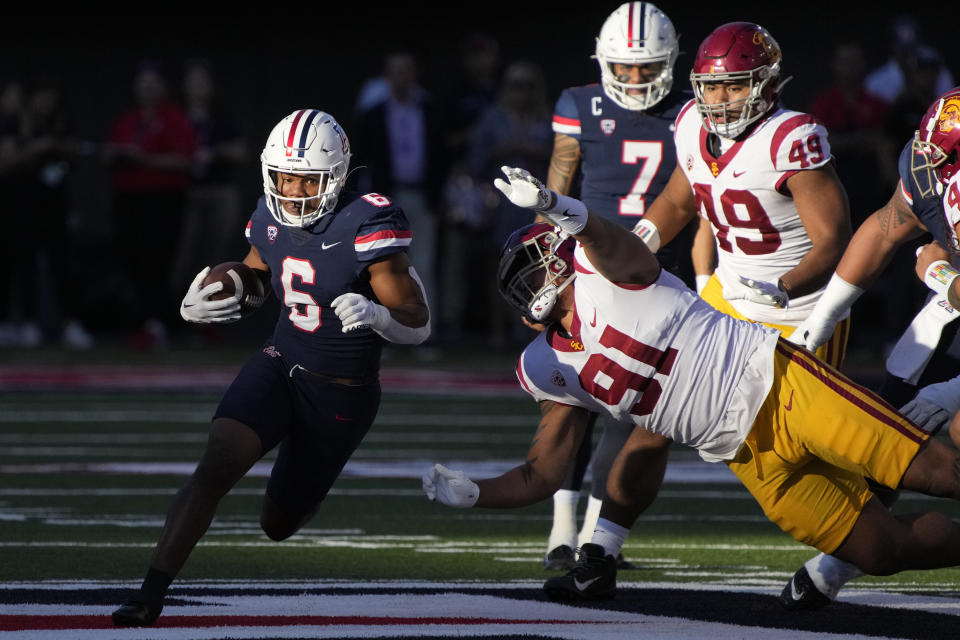 Arizona running back Michael Wiley (6) runs the ball by Southern California defensive lineman Tuli Tuipulotu (49) and defensive lineman Brandon Pili (91) in the first half during an NCAA college football game, Saturday, Oct. 29, 2022, in Tucson, Ariz. (AP Photo/Rick Scuteri)