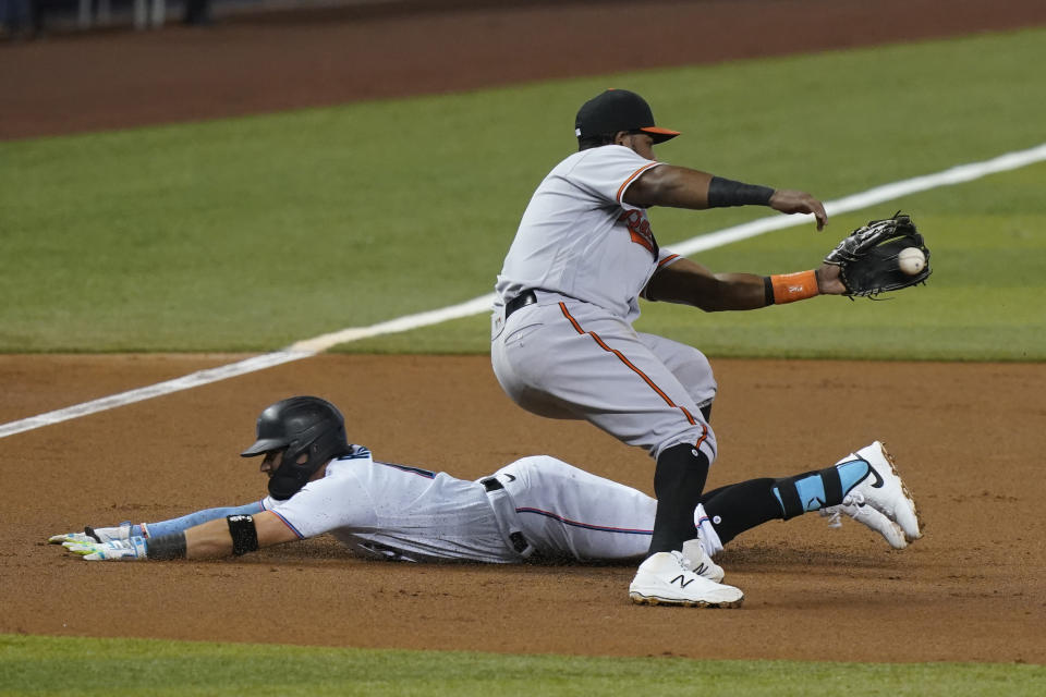 Miami Marlins' Miguel Rojas (19) slides into third base as Baltimore Orioles third baseman Maikel Franco (3) is late with the tag during the first inning of a baseball game, Tuesday, April 20, 2021, in Miami. (AP Photo/Marta Lavandier)