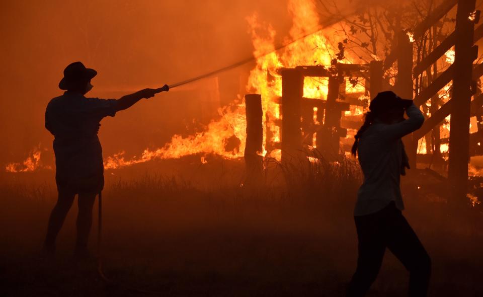 Residents defend a property from a bushfire at Hillsville near Taree, 350km north of Sydney on November 12, 2019. - A state of emergency was declared on November 11 and residents in the Sydney area were warned of "catastrophic" fire danger as Australia prepared for a fresh wave of deadly bushfires that have ravaged the drought-stricken east of the country. (Photo by PETER PARKS/AFP via Getty Images)