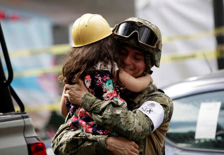 A girl hugs a Mexican marine officer as she offers hugs to people near the site of a collapsed building after an earthquake, in Mexico City. REUTERS/Jose Luis Gonzalez