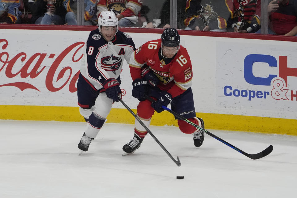 Columbus Blue Jackets defenseman Zach Werenski (8) and Florida Panthers center Aleksander Barkov (16) go after the puck during the first period of an NHL hockey game, Thursday, April 11, 2024, in Sunrise, Fla. (AP Photo/Marta Lavandier)